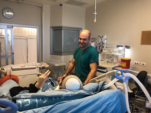 בתמונה, הנוירוכירורג ד״ר סמואל מוסקוויסי ונחום המסמן לו ״וי״ של ניצחון